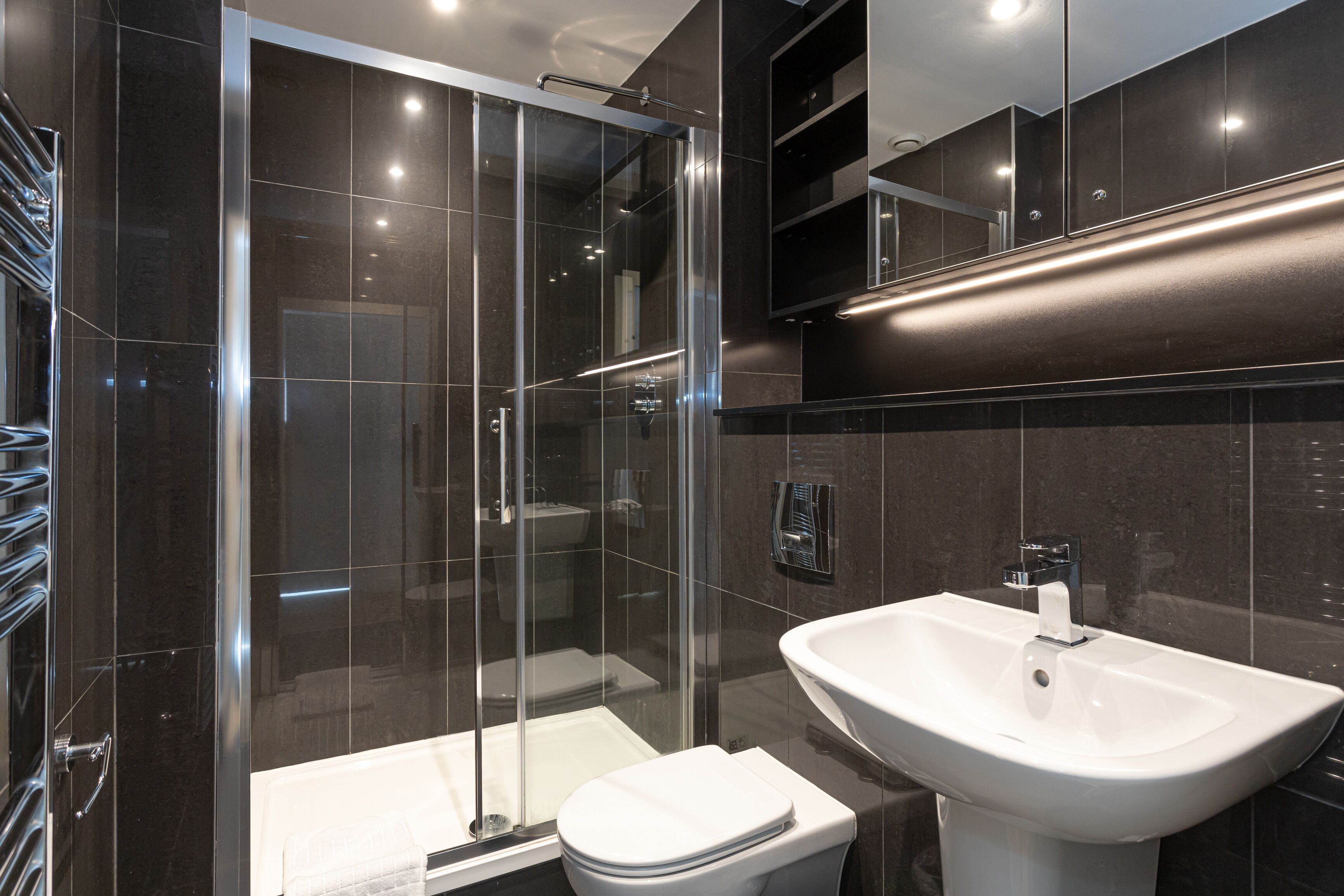 A modern bathroom with a glass-enclosed shower, a white toilet, and a white sink.