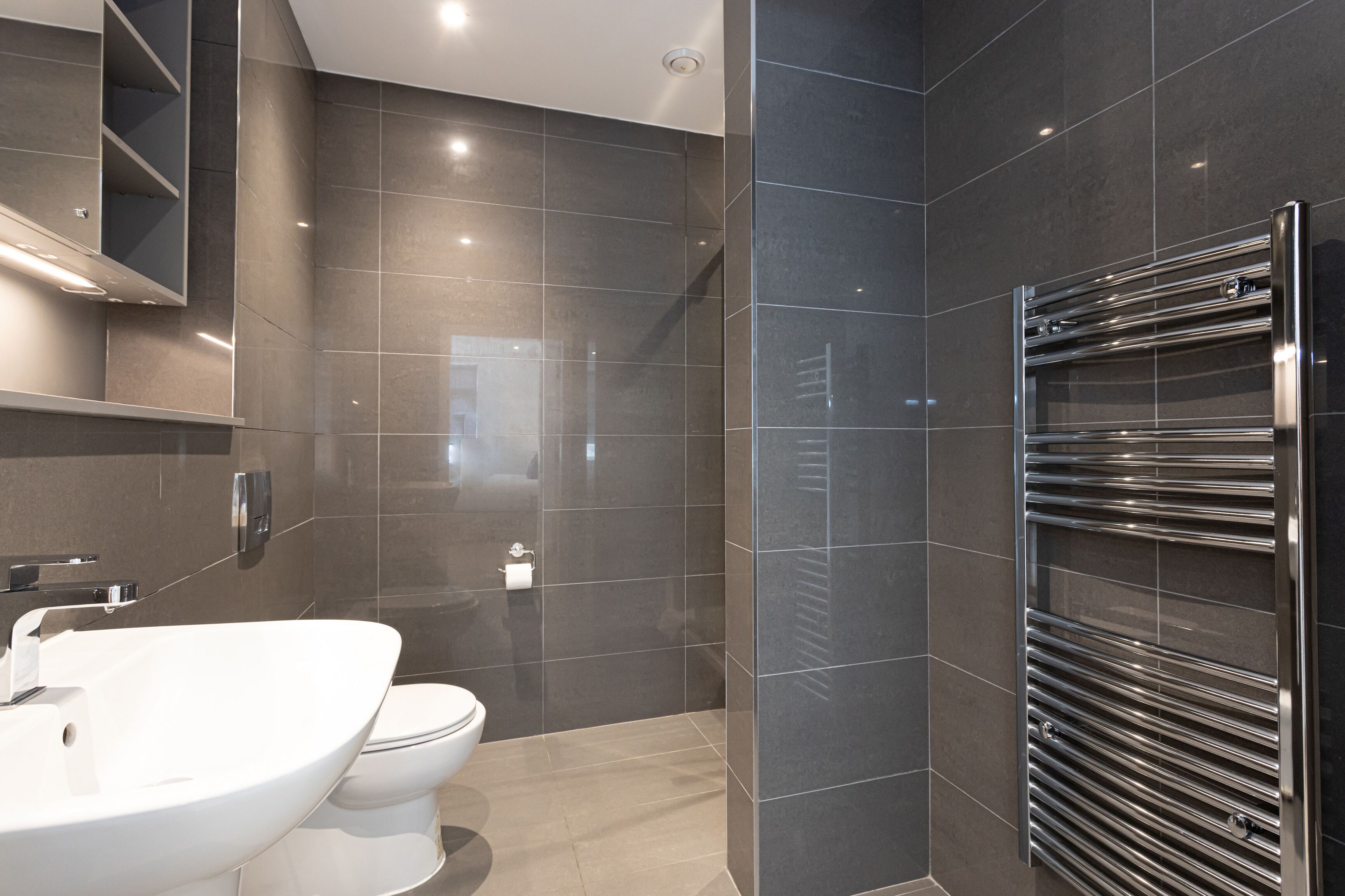 A modern bathroom with a double sink, toilet, and a glass shower enclosure.