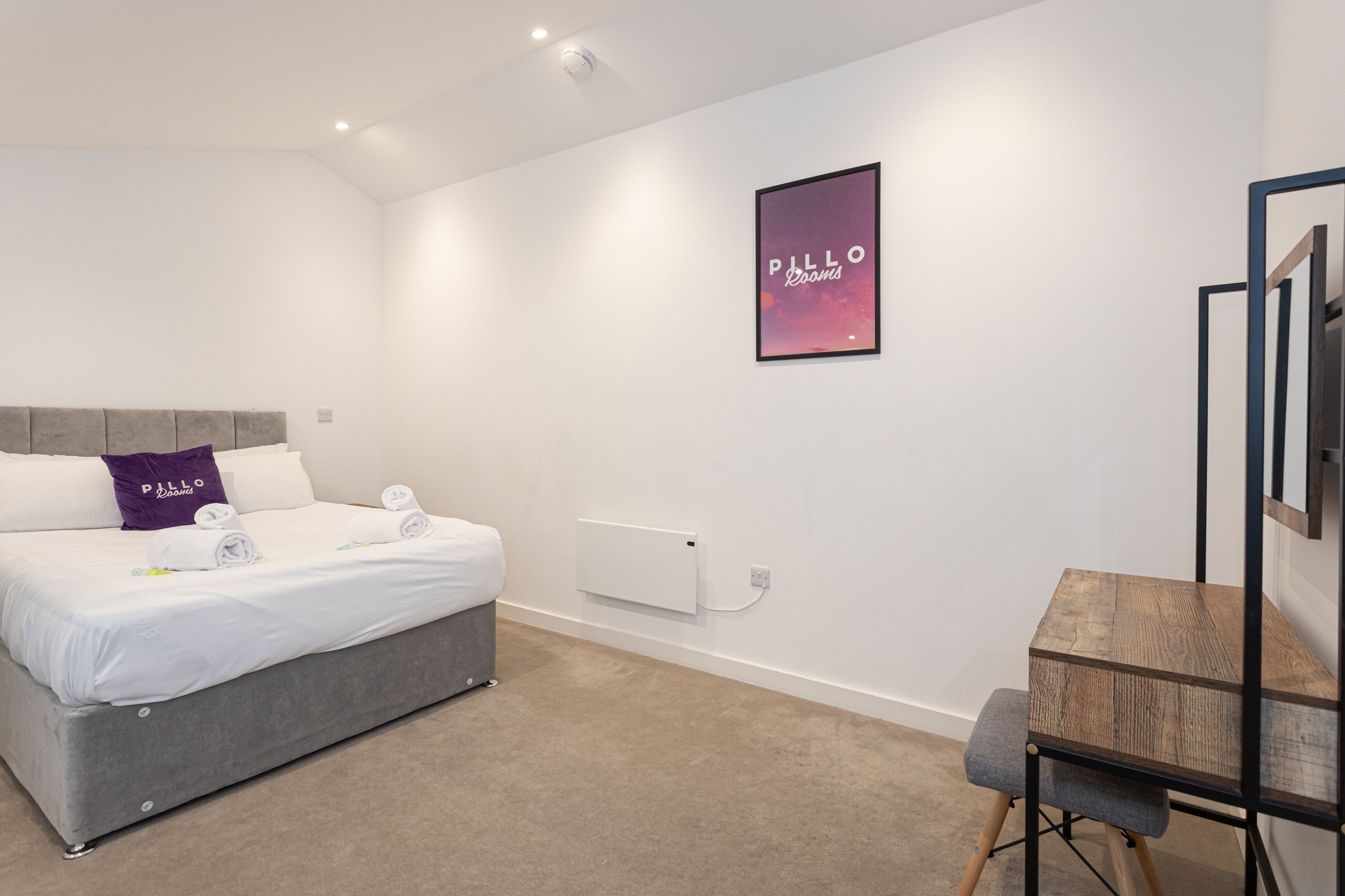 Une chambre d’hôtel moderne, équipée d’un lit, d’un bureau et d’un radiateur.