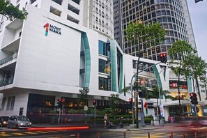 A modern building with a prominent 'Mont Kiara' sign, featuring a unique architectural design with curved lines and large windows.