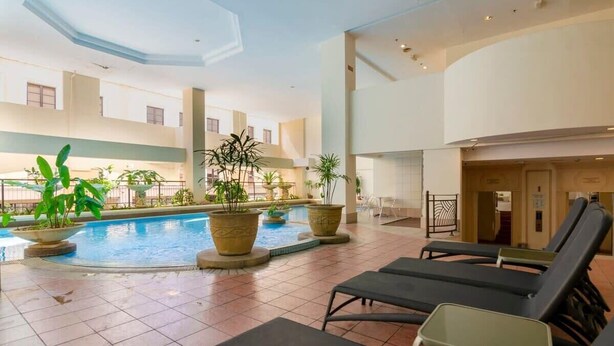 Ein Hallenbad mit Liegestühlen, Topfpflanzen und modernem architektonischem Design.