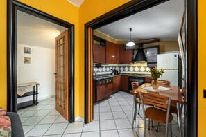 Eine Küche mit Holzausstattung, einer gefliesten Spritzschutzwand und einem Essbereich mit Stühlen und einem Tisch.