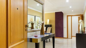 Ein Hotelzimmer mit Holztür, einem Tisch mit einer Vase und einer Schale, einem Spiegel, der den Raum reflektiert, und einer violetten Akzentwand.