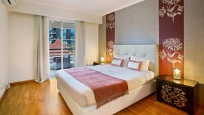 Ein Schlafzimmer mit einem großen Bett, einem Nachttisch mit Lampe, einer Schiebetür und Blick ins Freie.