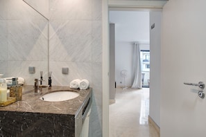 Un baño moderno con un lavamanos de mármol, dos toallas y un ventilador.