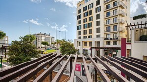 Un immeuble à plusieurs étages doté de balcons, une enseigne bien visible indiquant la présence d’un restaurant, et un ciel dégagé.