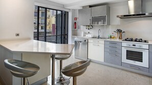 Ett modernt kök med en central köksö, rostfria vitvaror och utsikt genom en skjutdörr.