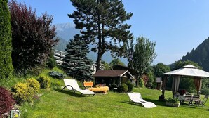 A grassy outdoor area with lounge chairs, a wooden boat, and a gazebo. - Apartment "Casa Nova" with Mountain View & Private Garden (Ponte Rendena)