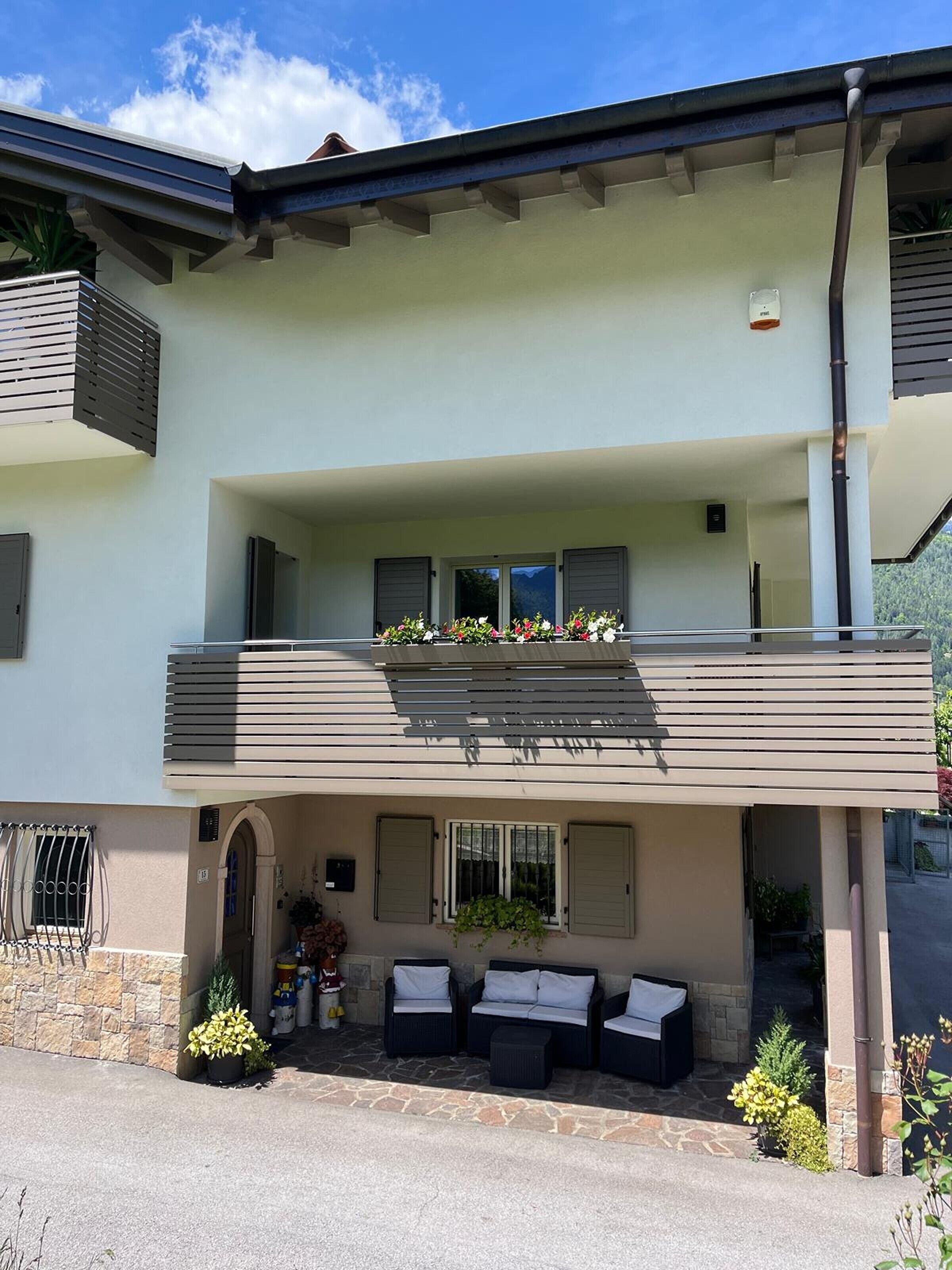 A two-story building with a balcony, outdoor seating, and a stone facade.