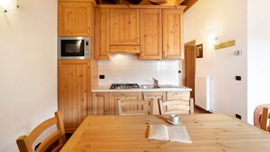 Una cucina con mobili in legno, un forno a microonde, un fornello e un tavolo da pranzo con sedie.