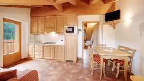 Une cuisine en bois, dotée de placards, d’un four à micro-ondes et d’un coin repas avec des chaises et une table.