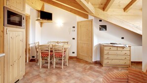 Une pièce avec des meubles de rangement en bois, une table à manger avec des chaises, un téléviseur et une commode en bois.