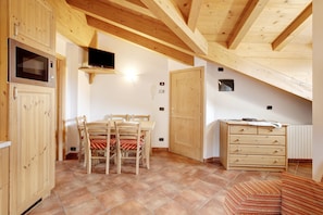 Une pièce avec des meubles de rangement en bois, une table à manger avec des chaises, un téléviseur et une commode en bois.
