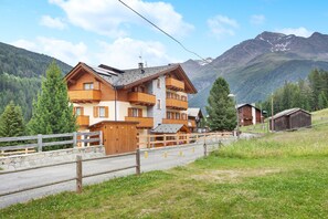 Un chalet de madera de varios pisos con balcones, con montañas al fondo.