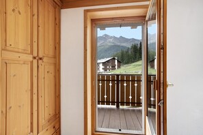 A wooden door leading to a balcony with a view of mountains and houses. - Apartment 'Casa Michela Bilocale 2' with Mountain View, Shared Terrace and Wi-Fi (Valfurva)