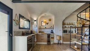 Una cocina con armarios de madera, horno empotrado, microondas y una lámpara colgante.