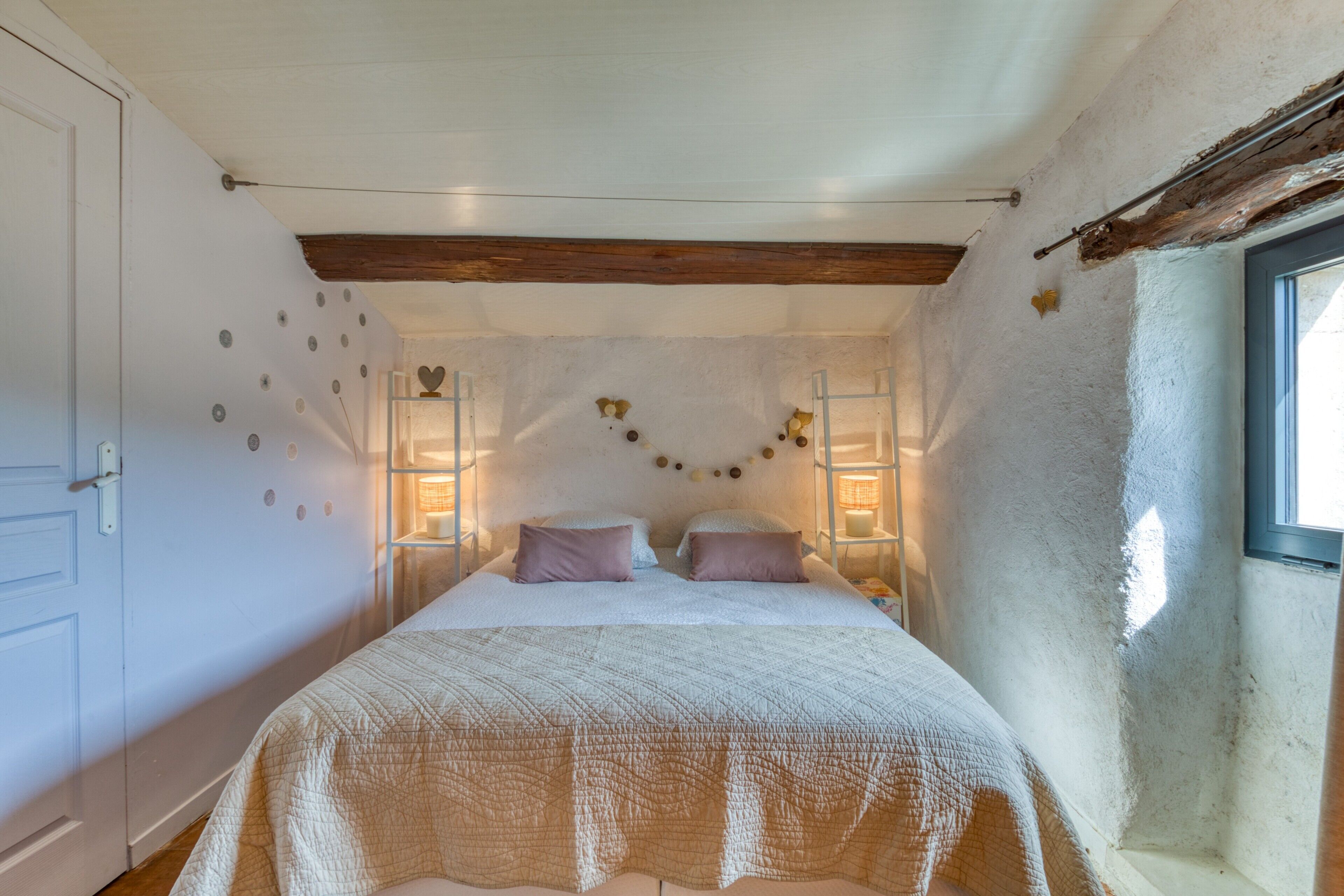 Ein Schlafzimmer mit einem Bett, zwei Nachttischen, einem Fenster und einer Tür.