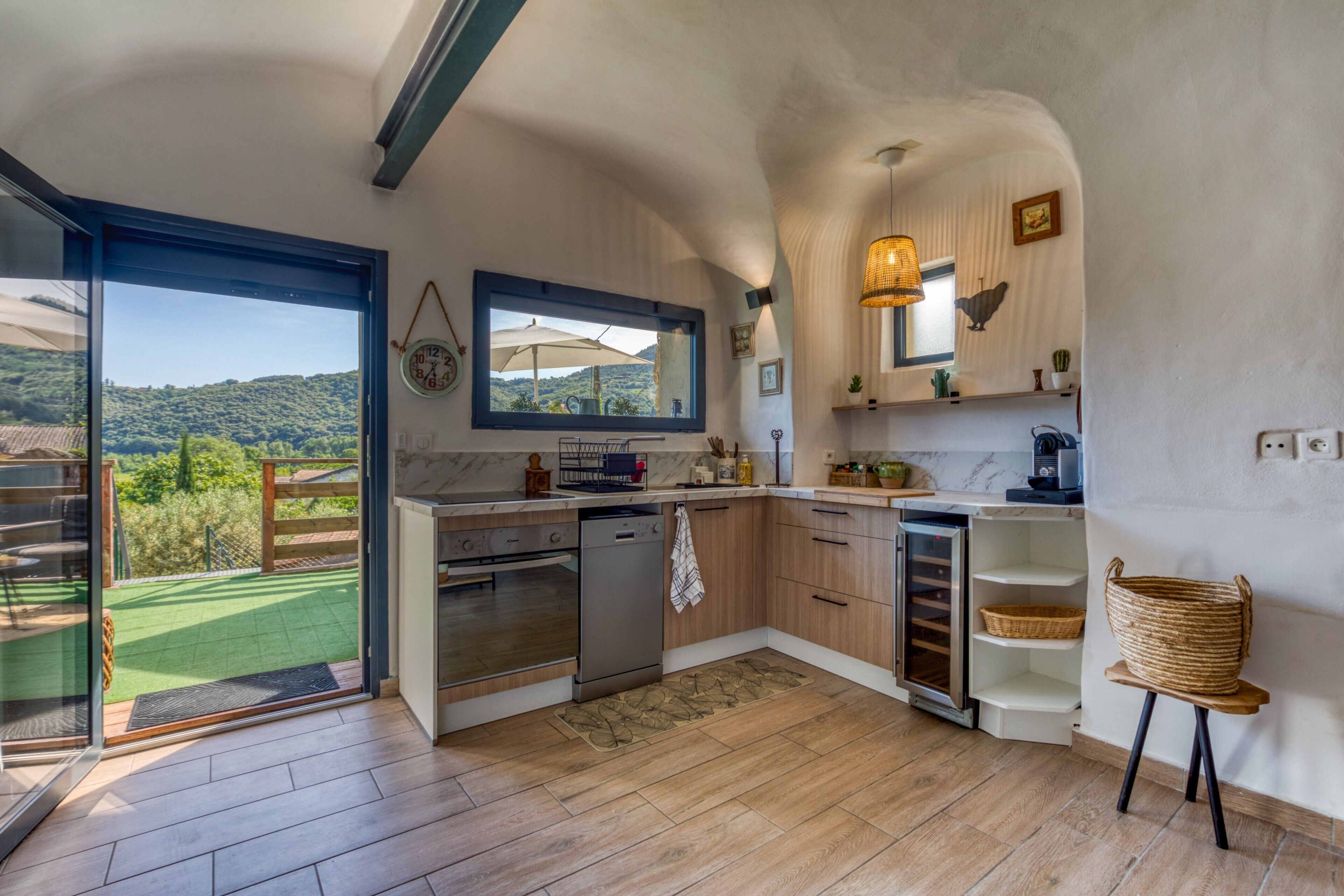A kitchen with a view of a green landscape, wooden cabinets, a built-in oven, and a sink.