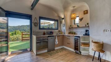 A kitchen with a view of a green landscape, wooden cabinets, a built-in oven, and a sink.