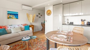 Ein modernes Wohnzimmer mit einer Couch, einem Couchtisch und einem Esstisch für zwei Personen.