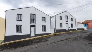 Een rij witte gebouwen met zwarte accenten, een verharde straat en een bewolkte lucht.