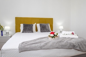 A neatly made bed with a white duvet, two grey pillows, and a yellow headboard.