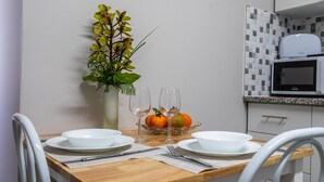 Een eettafel met witte borden, twee wijnglazen en een vaas met groene bladeren.
