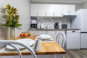 A modern kitchen with white cabinets, a microwave, a coffee maker, and a dishwasher.