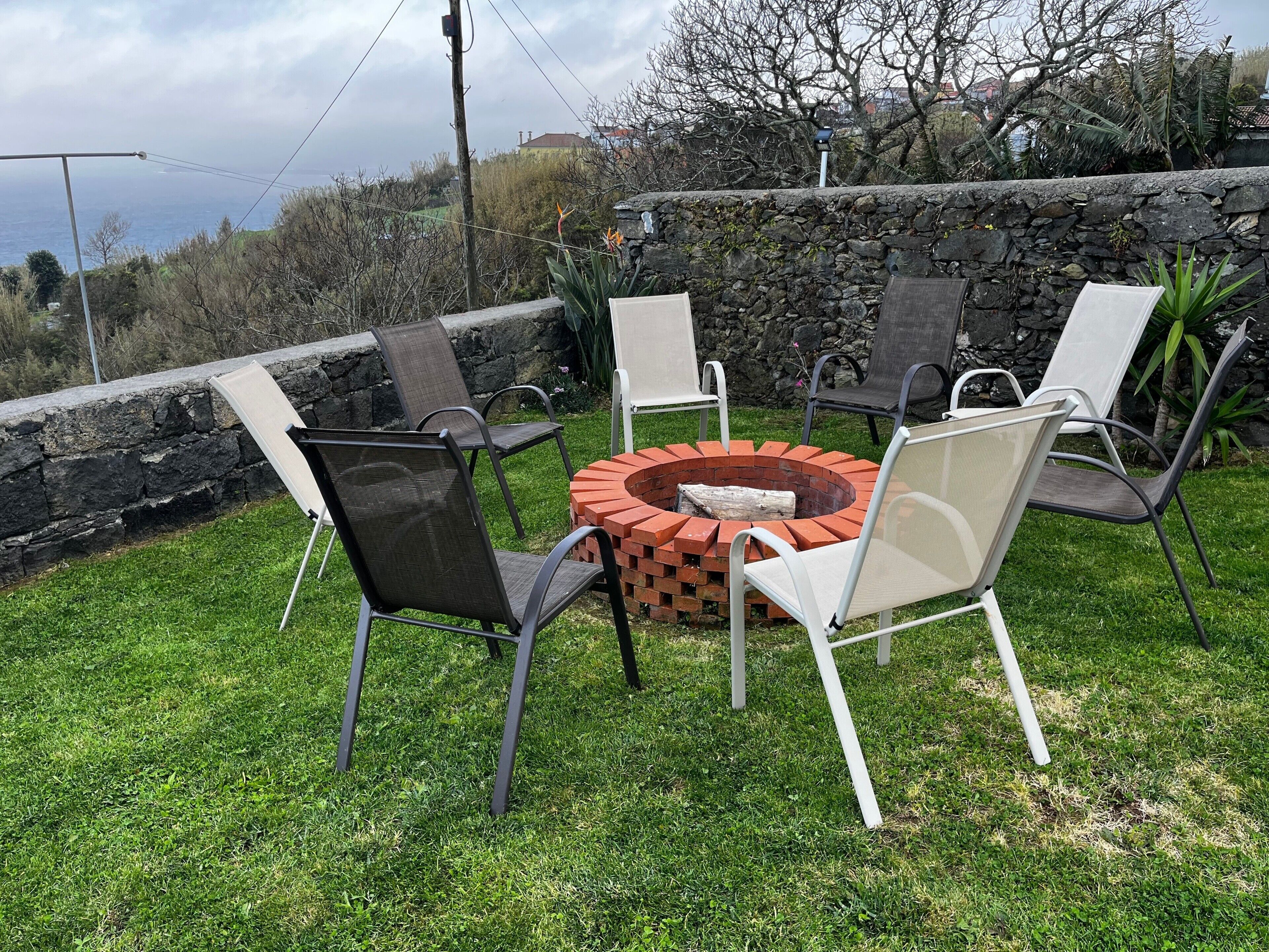 A circular outdoor seating area with a fire pit, surrounded by four chairs.