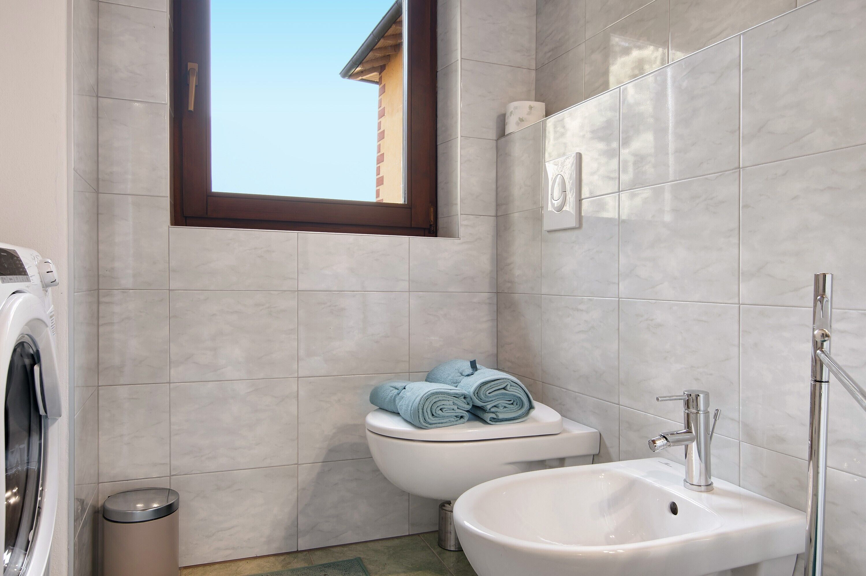 A bathroom with a toilet, sink, and window.