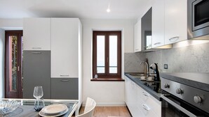 A modern kitchen with a built-in oven, stainless steel appliances, and a window overlooking a body of water. - Apartment 'Fogazzaro Lake View' with Lake View, Wi-Fi and Air Conditioning (Albogasio-Oria Valsolda)