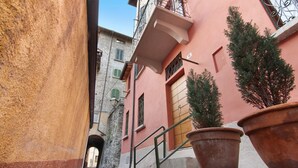 A narrow street with a building featuring a wooden door and a balcony. - Apartment 'Fogazzaro Lake View' with Lake View, Wi-Fi and Air Conditioning (Albogasio-Oria Valsolda)