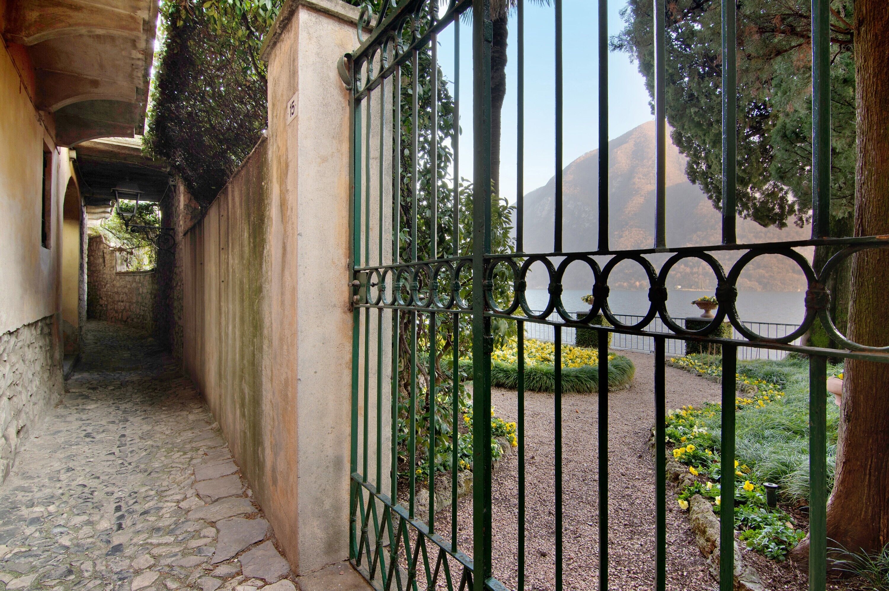 Un camí de pedra condueix a una entrada tancada amb un paisatge de muntanyes al fons.