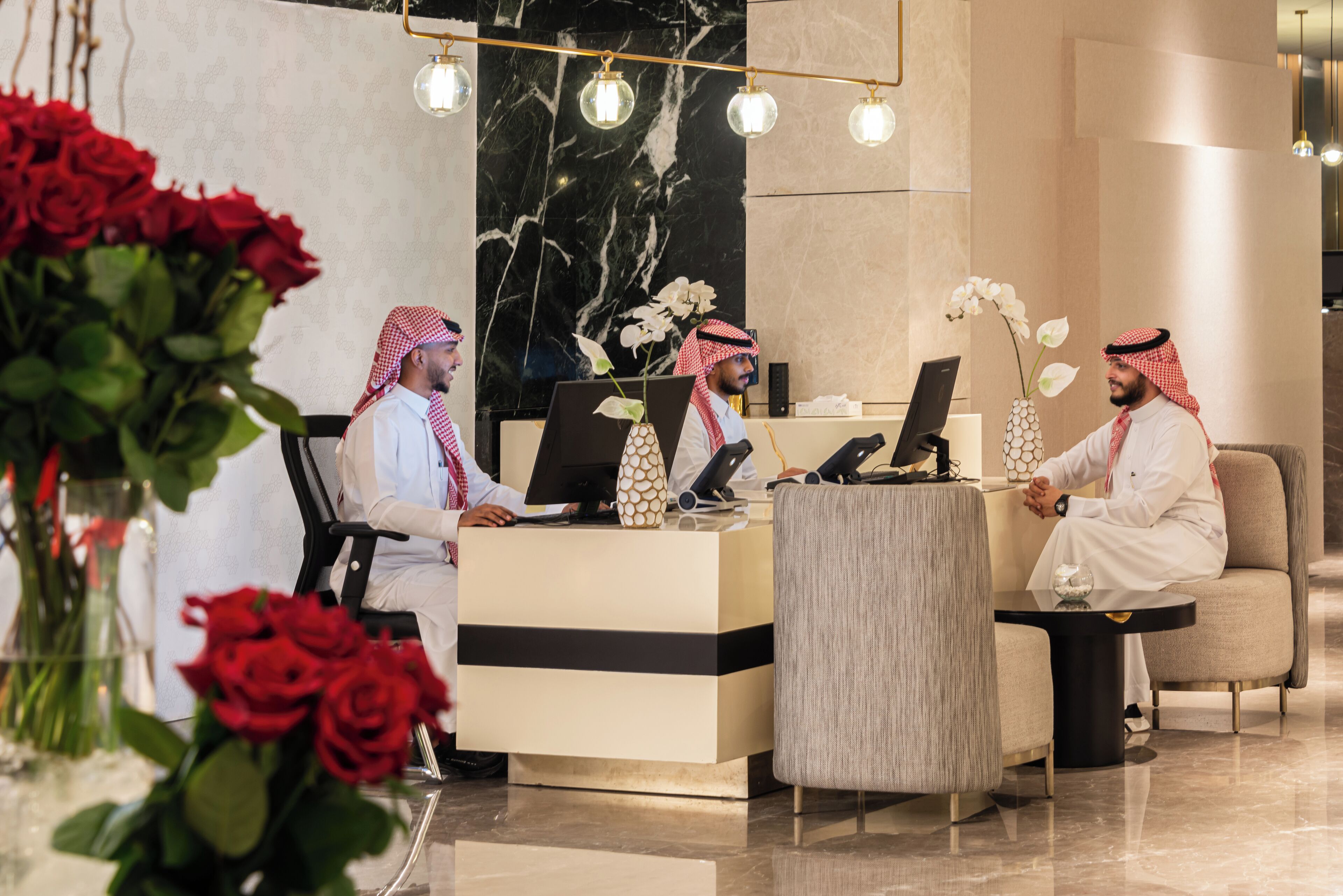 A reception area with a marble wall, a reception desk, and two seating areas.