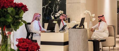 A reception area with a marble wall, a reception desk, and two seating areas.