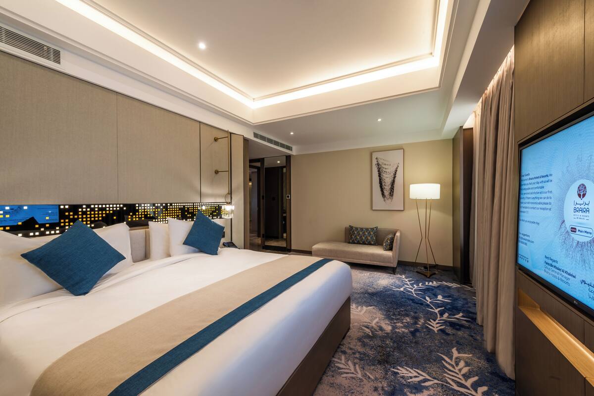 Una habitación de hotel con una cama grande, un sofá, un televisor y piso alfombrado.