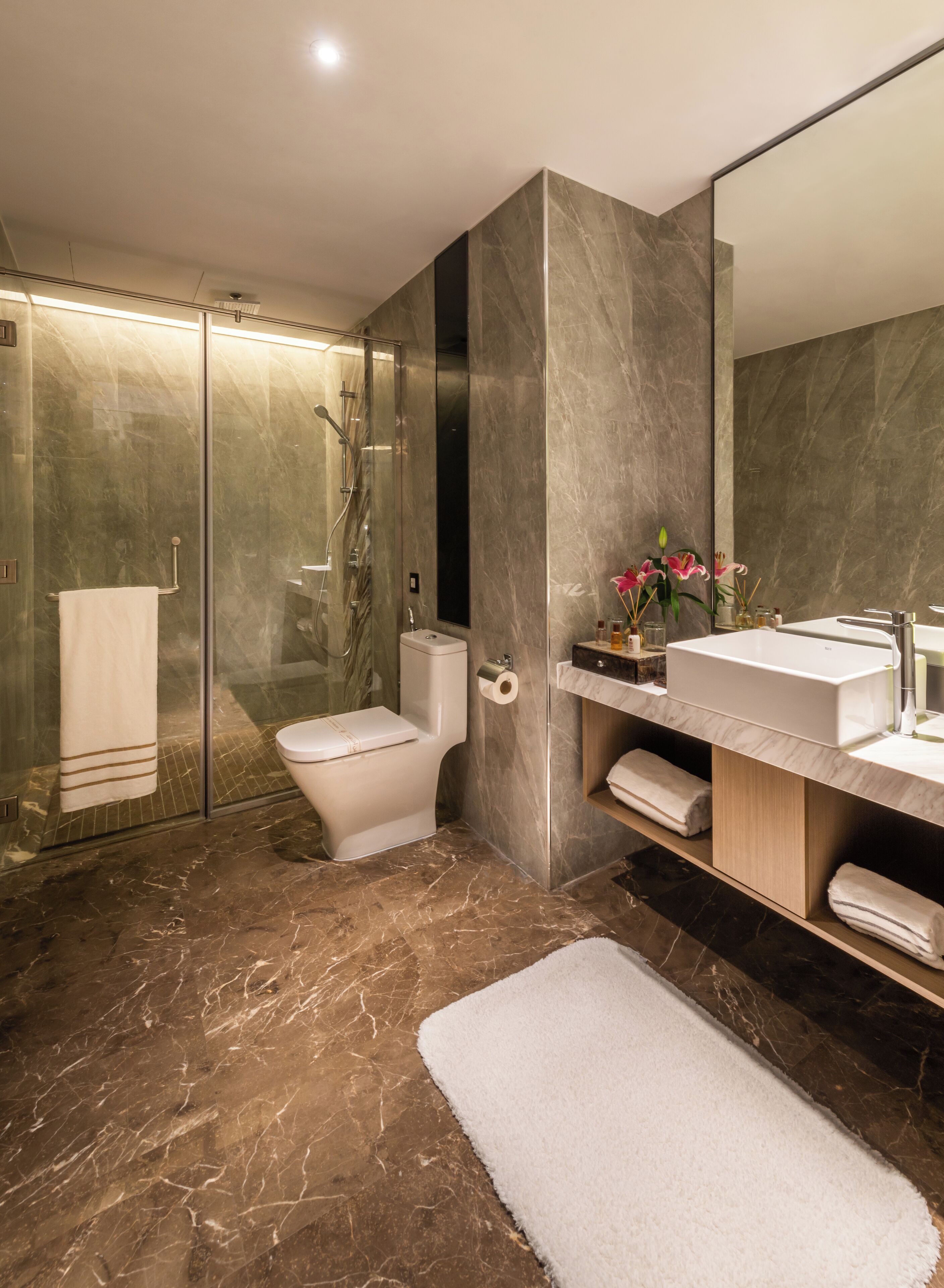 Une salle de bain moderne avec une douche à parois de verre, des toilettes et un meuble-lavabo avec un miroir.