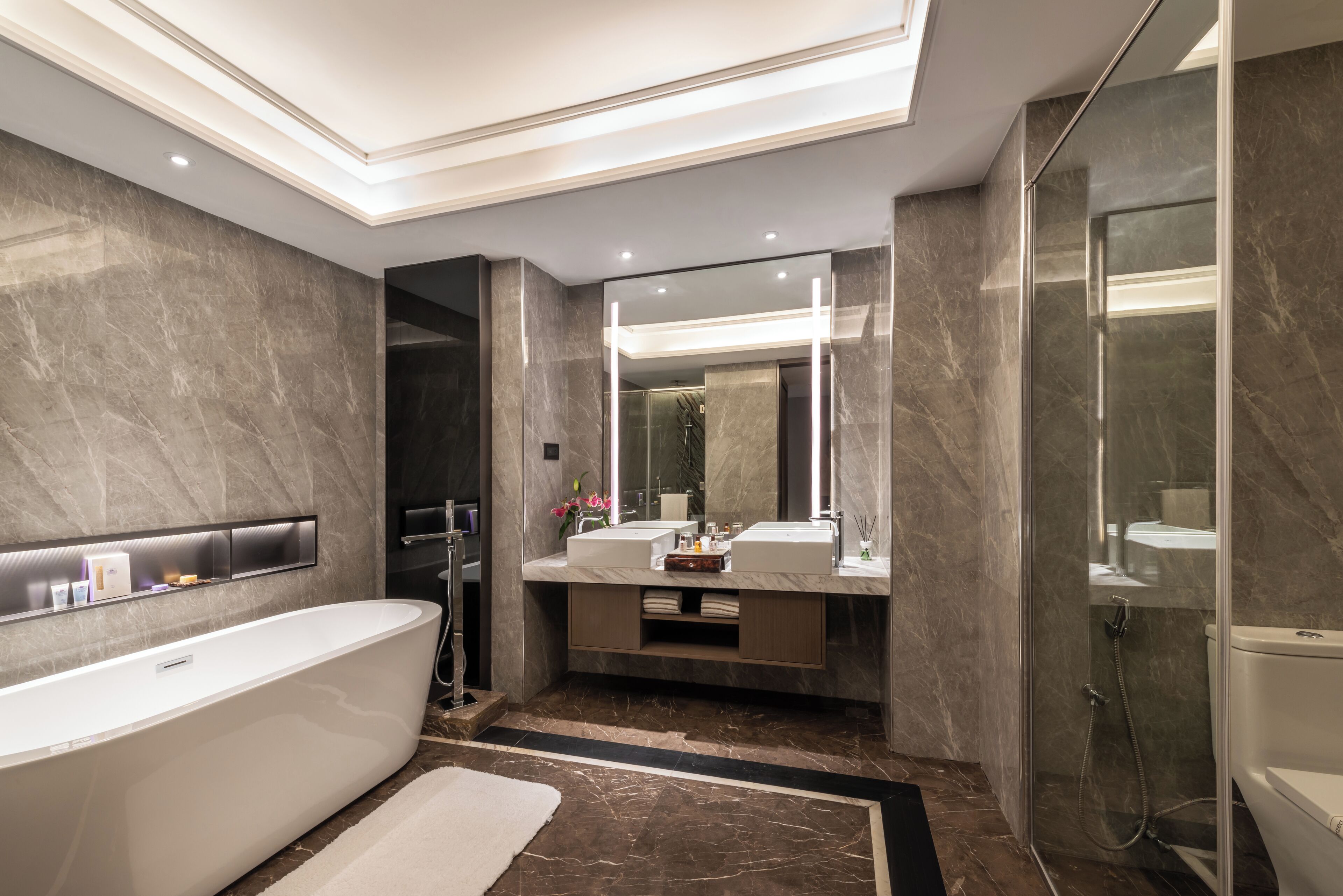 A modern bathroom with a freestanding bathtub, a glass-enclosed shower, and a vanity with a large mirror.