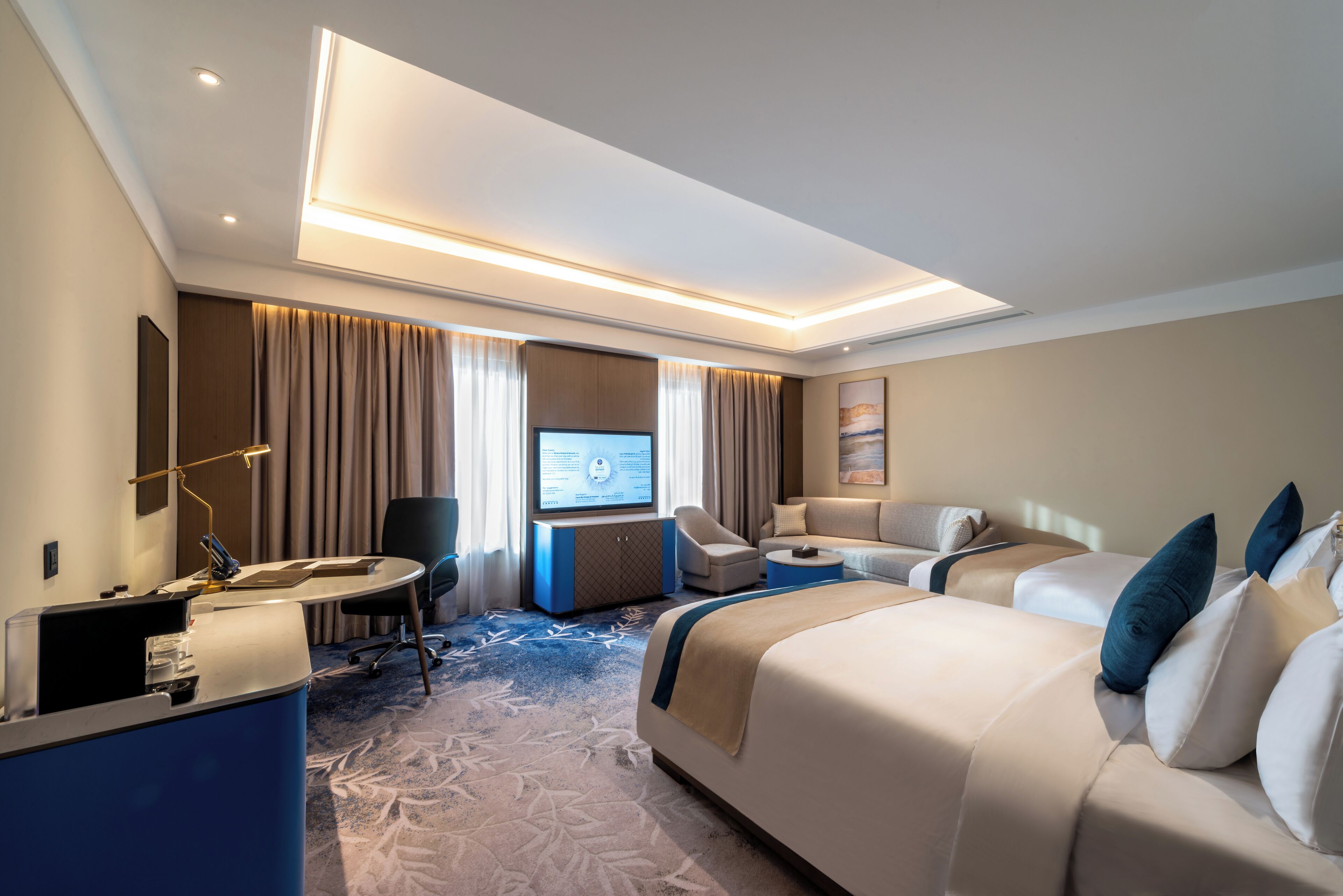 Ein modernes Hotelzimmer mit einem großen Bett, einem Schreibtisch, einem Fernseher und einer Sitzecke.