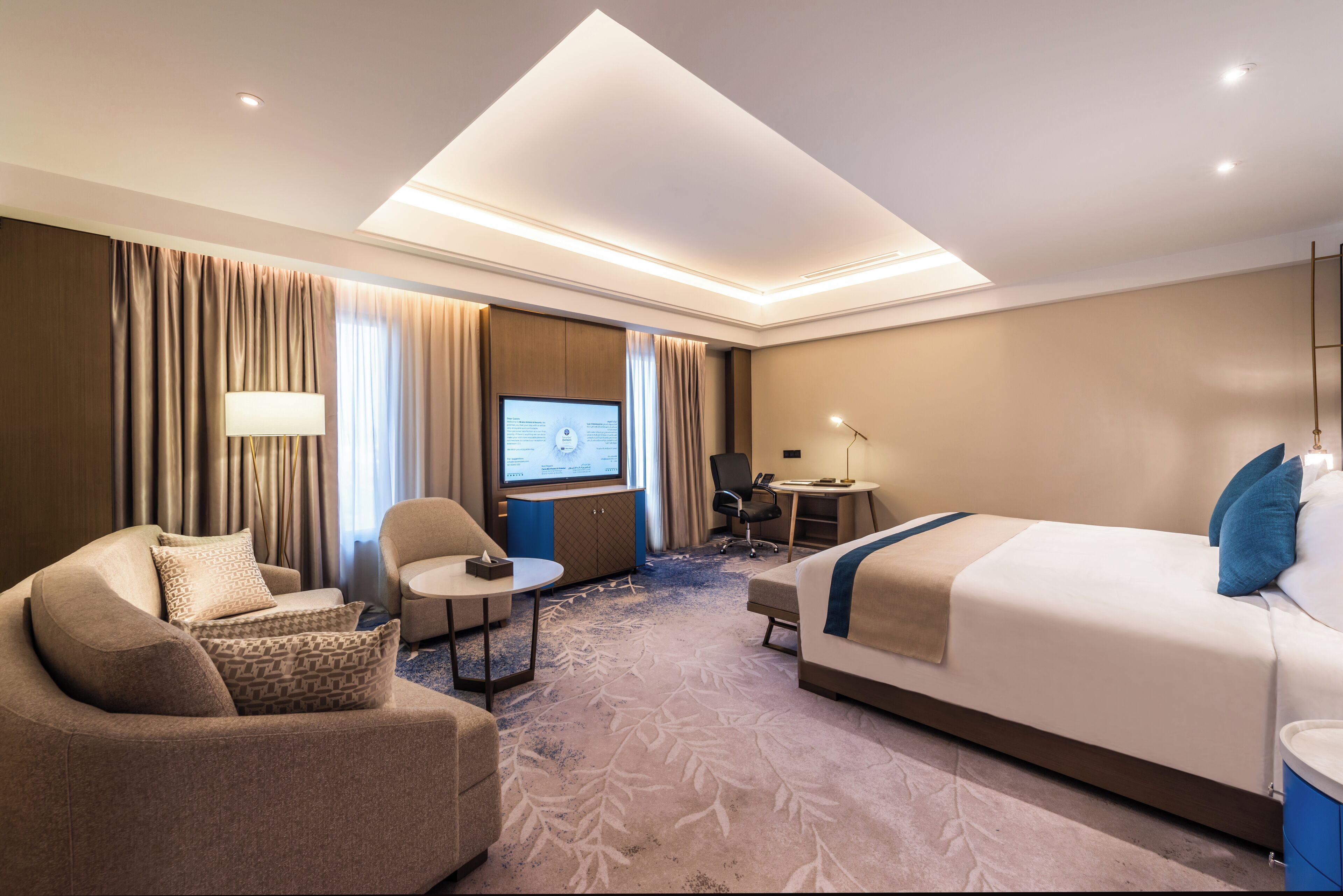 A hotel room with a bed, a sofa, a desk, and a TV.