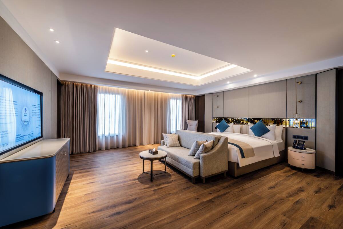Una habitación de hotel moderna con una cama grande, un sofá, un televisor y un escritorio.