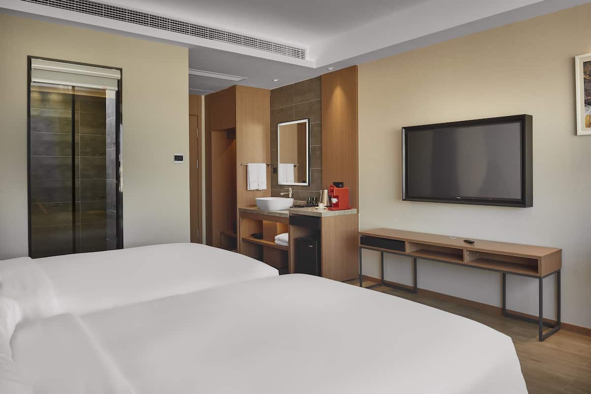 A hotel room with a large bed, a desk, a sink, and a TV.