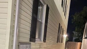 A narrow outdoor pathway leading to a building with a light-colored exterior and dark shutters on the windows.