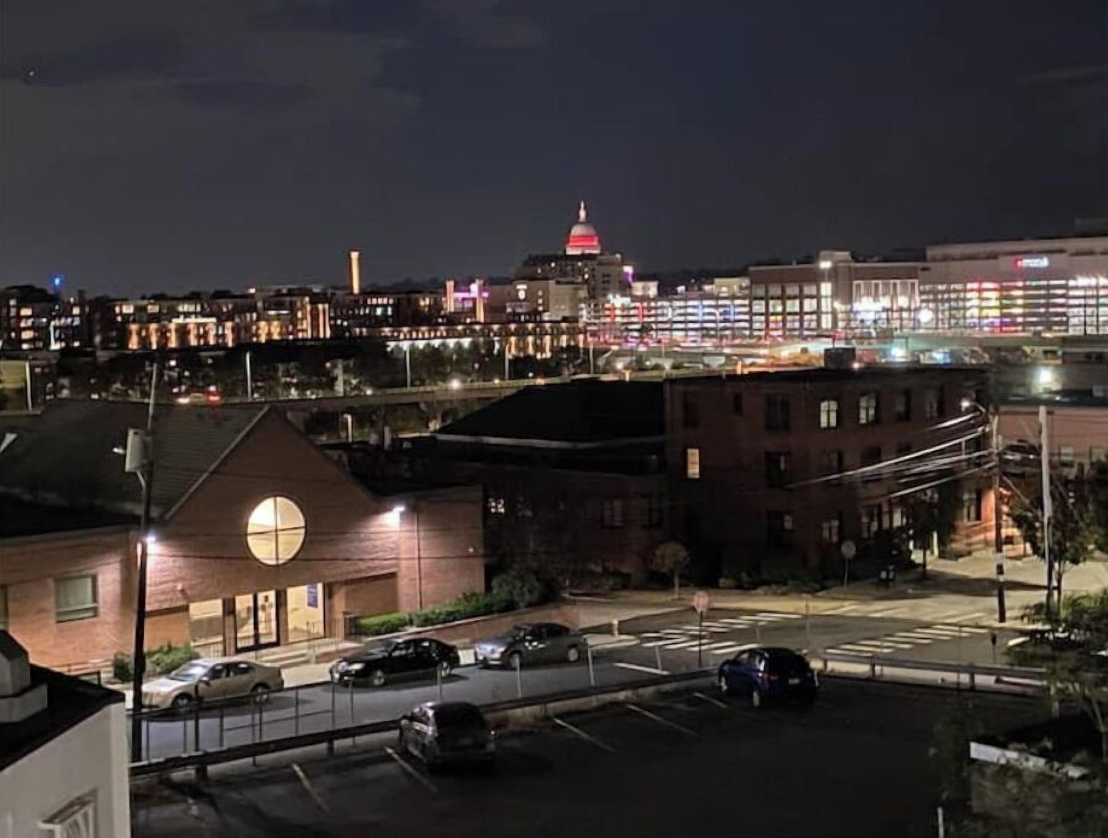 A nighttime cityscape with a prominent building with a red dome and illuminated windows.
