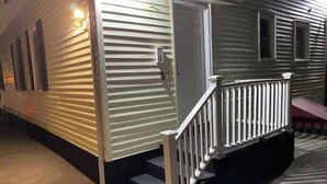 A mobile home with a front porch and a staircase leading to the entrance.