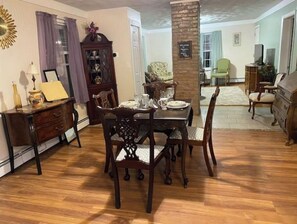 Un comedor con una mesa y sillas de madera, un mueble aparador y un espejo decorativo.