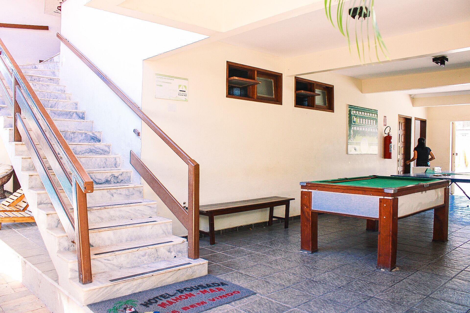Un hall d’hôtel avec une table de billard, un escalier et un banc.