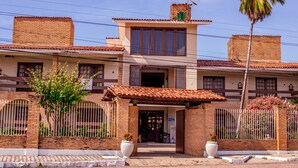 Un edificio de dos pisos con techo de tejas, una chimenea de ladrillo y una entrada con portón.
