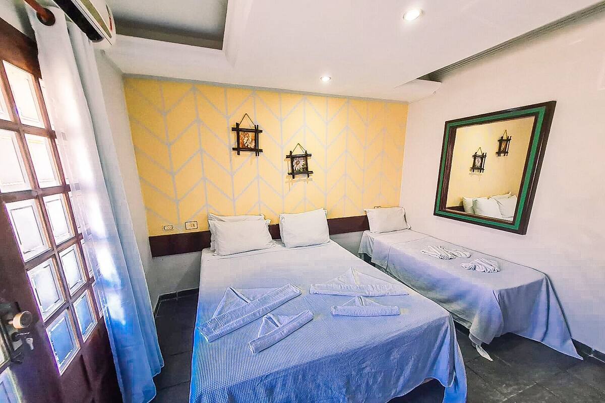 A hotel room with two beds, a large mirror, and a window with curtains.