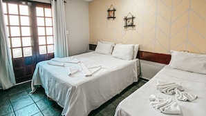 Habitación de hotel con dos camas, una ventana con cortinas, aire acondicionado montado en la pared y un papel tapiz estampado.